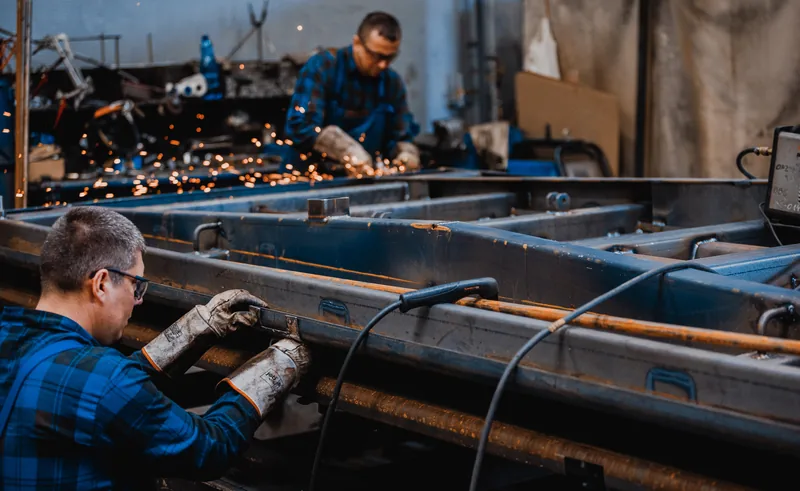 Produkcja przyczep CARGO Promodis — wykwalifikowana polska kadra Polscy spawacze produkujący przyczepy rolnicze CARGO Promodis w zakładzie produkcyjnym w Polsce